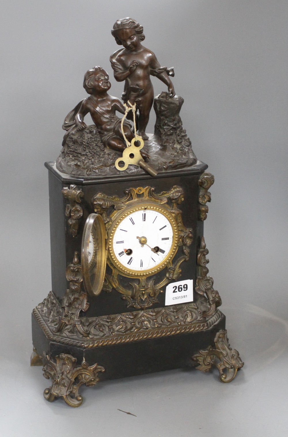 A Victorian bronze mounted black slate mantel clock, with enamelled dial, surmounted with figures of putti, height 48cm
